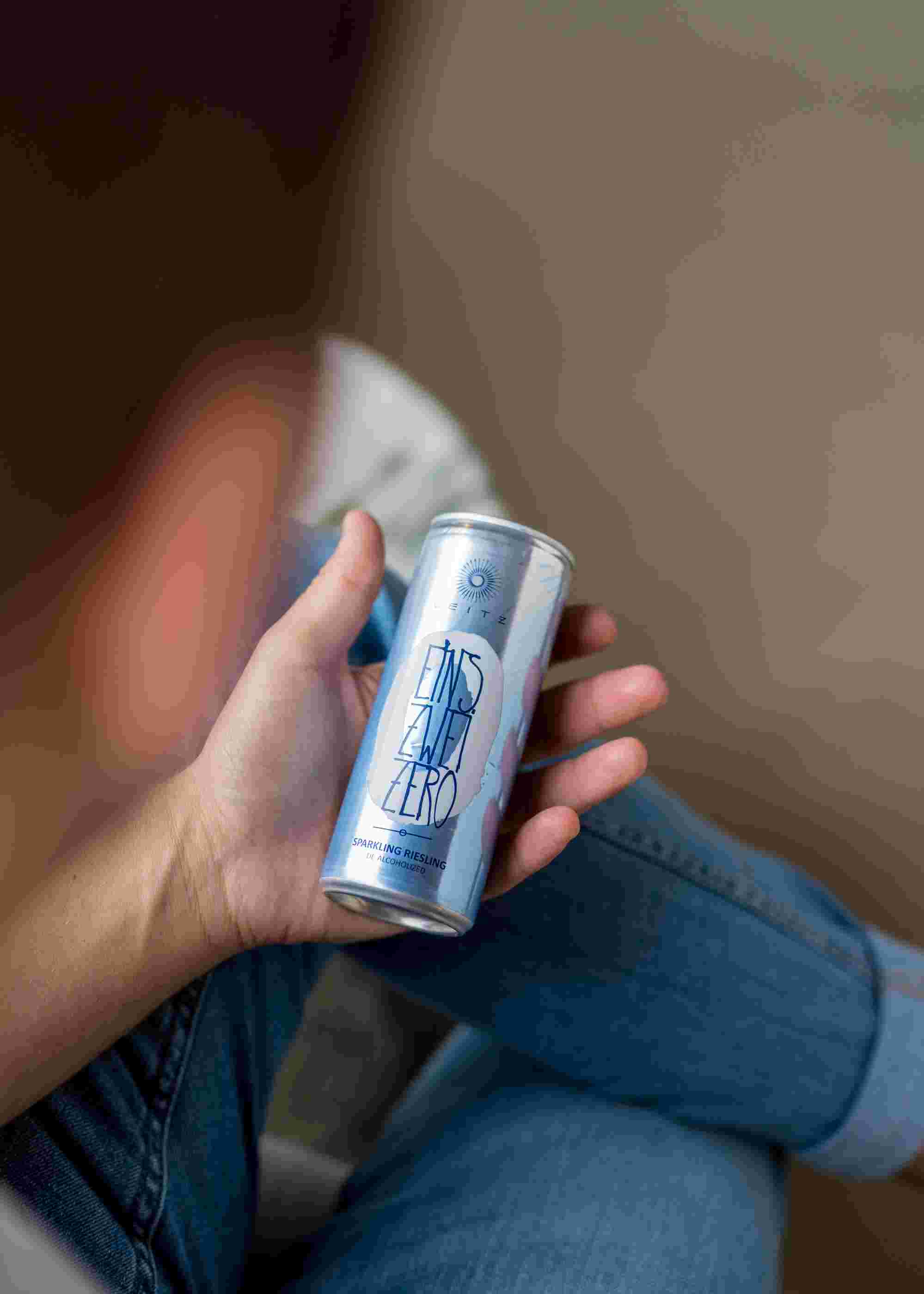 Sfeerfoto blikje Leitz Eins-Zwei-Zero Riesling Sparkling. Een man houdt het blikje Eins Zwei Zero Sparkling Riesling vast in zijn hand.