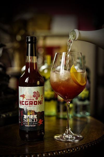 Sfeerfoto van een fles Virgin Negroni Dark Shed Distillery. De Virgin Negroni Dark Shed Distillery wordt ingeschonken in een mooi glas.