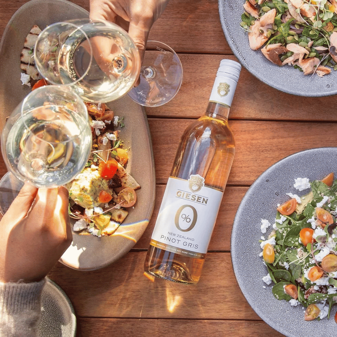 Giesen 0.0 Pinot Gris alcoholvrije wijn in een fles, met een elegant glas met roze grapefruit en een pink aperitief.