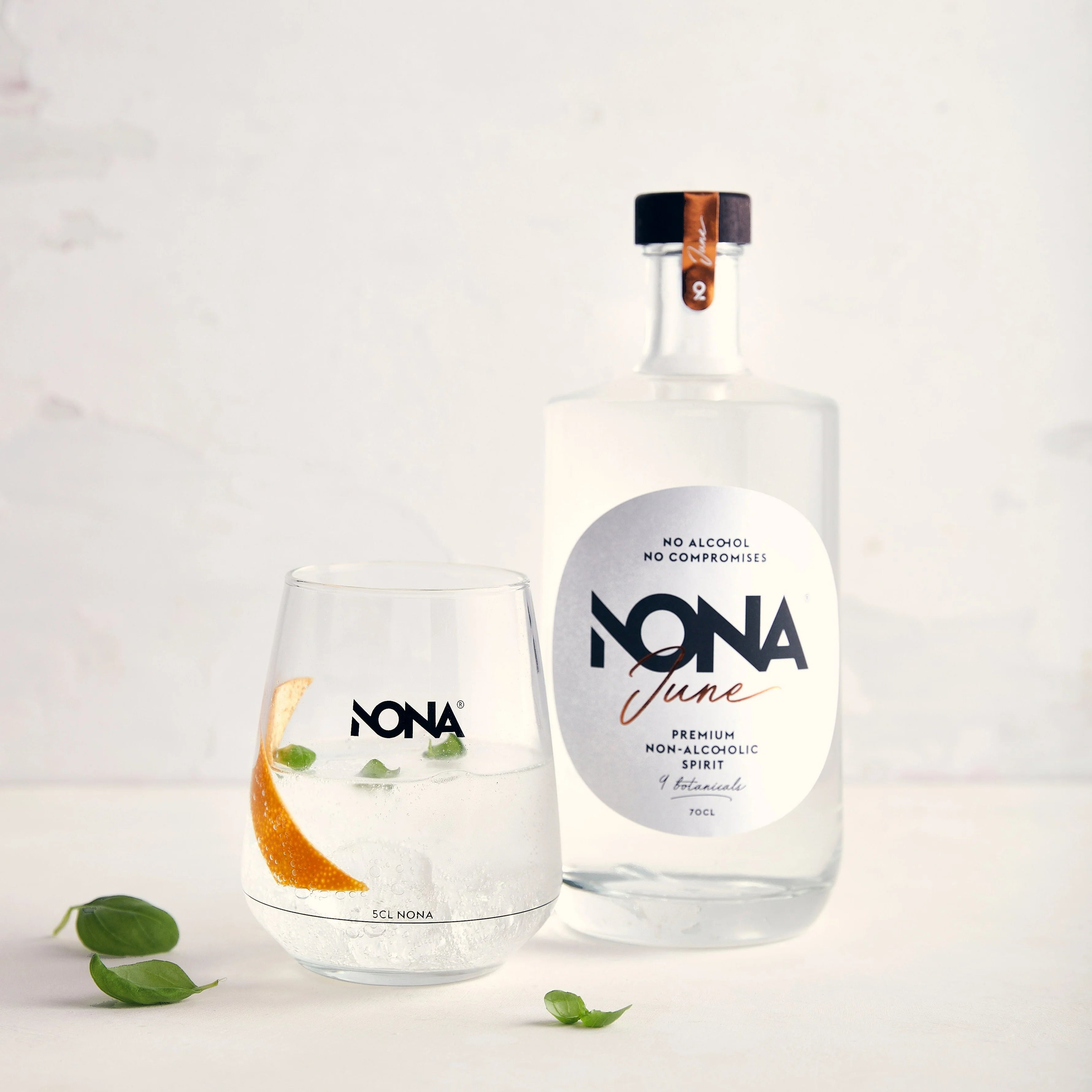 Sfeerfoto van een fles NONA June 70cl. Links staat een glas met daarin de Nona June. 